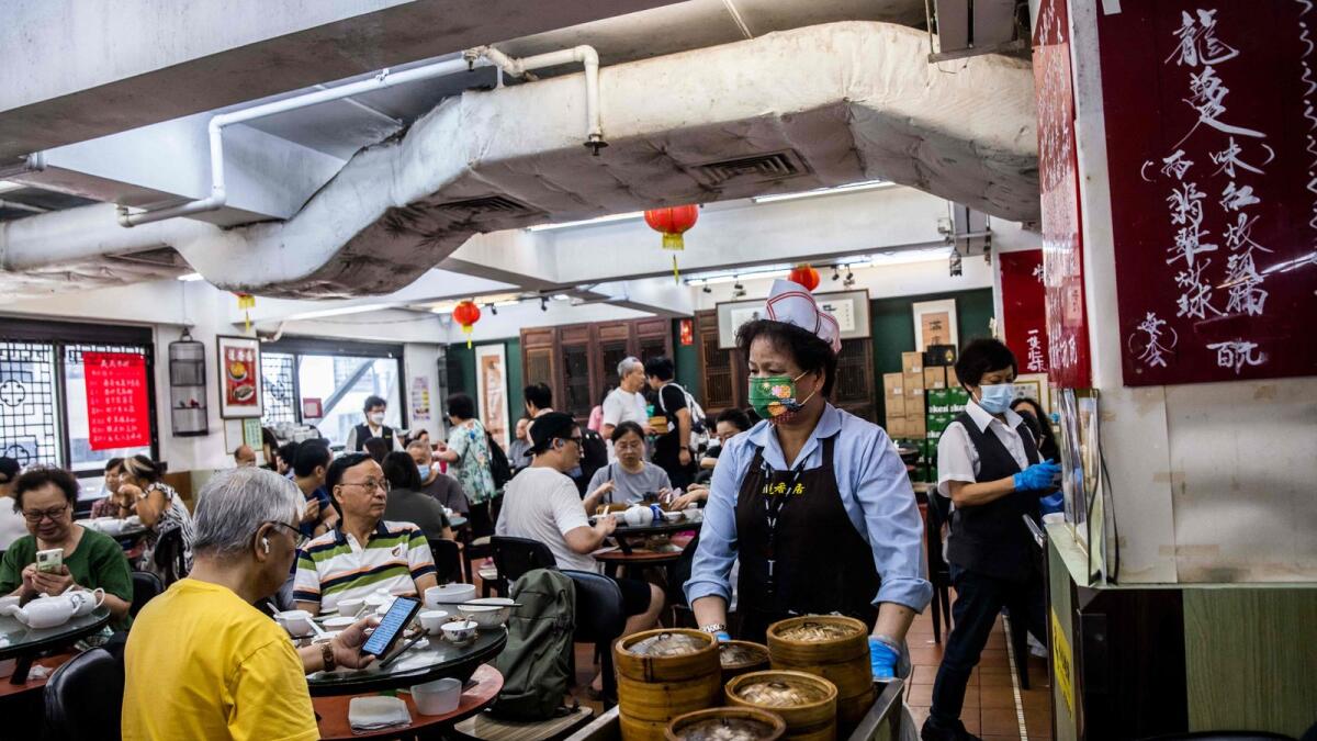 عامل يدفع صينية من Yum Cha ، وجبة فطور وغداء كانتونيز تتضمن شاي وديم سوم ، في مطعم في هونغ كونغ.  - وكالة فرانس برس