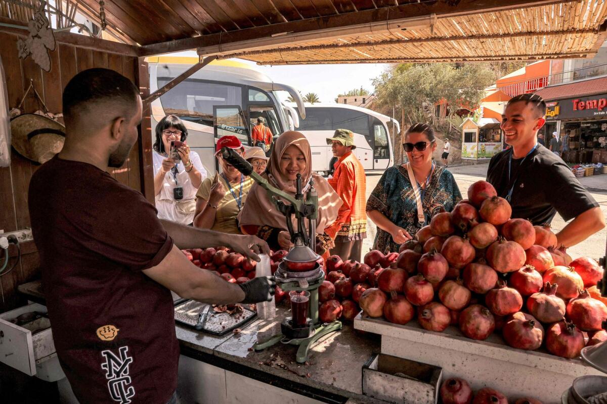 بائع يعصر عصير الرمان الطازج للعملاء والسياح في كشك في مدينة أريحا الفلسطينية في الغرب المحتل في 27 سبتمبر 2023. — AFP