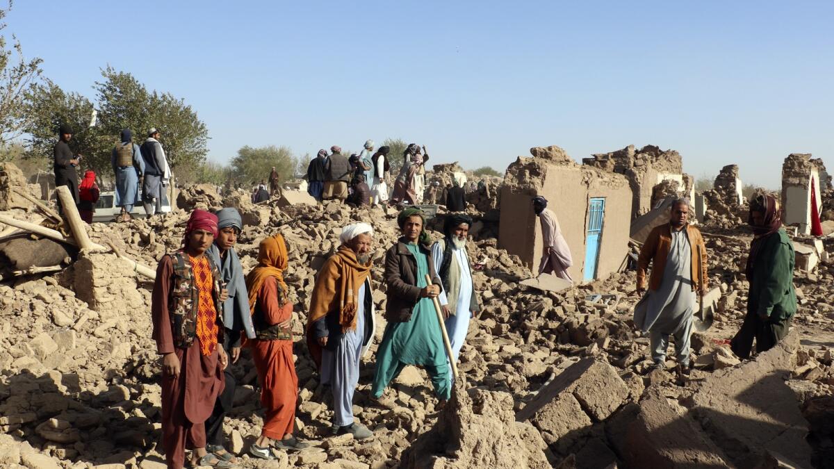 أفغان يقفون في فناء منازلهم المدمرة بعد الزلزال الذي ضرب منطقة زندا جان في مقاطعة هرات.  — ا ف ب