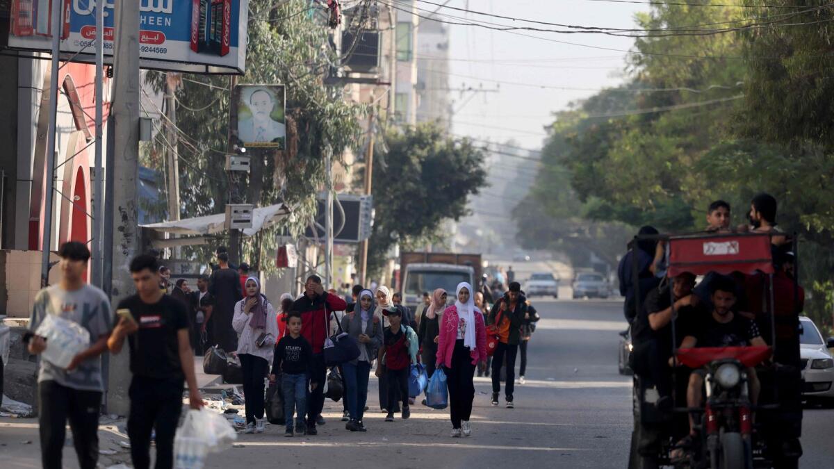 فلسطينيون يحملون أمتعتهم يفرون إلى مناطق أكثر أمانًا في مدينة غزة بعد الغارات الجوية الإسرائيلية، في 13 أكتوبر 2023. دعت إسرائيل إلى النقل الفوري لـ 1.1 مليون شخص في غزة وسط قصفها المكثف ردًا على هجمات حماس، مع تحذير الأمم المتحدة من العواقب 