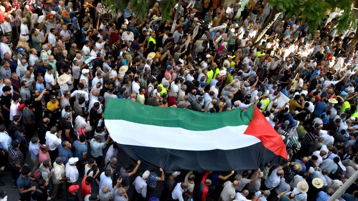 متظاهرون يرفعون علمًا فلسطينيًا كبيرًا خلال مظاهرة مناهضة لإسرائيل في تونس.  – وكالة فرانس برس