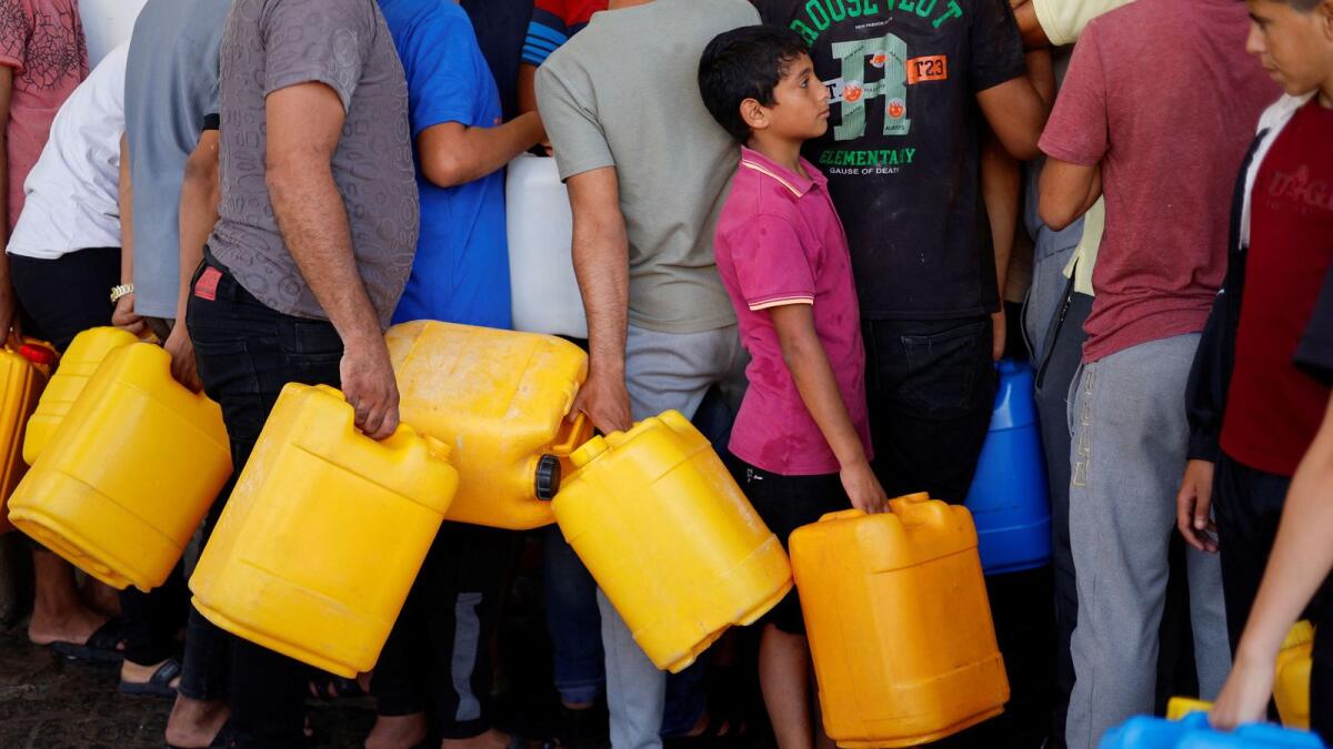 فلسطينيون يتجمعون لجمع المياه في خان يونس جنوب قطاع غزة يوم الأحد.  – رويترز