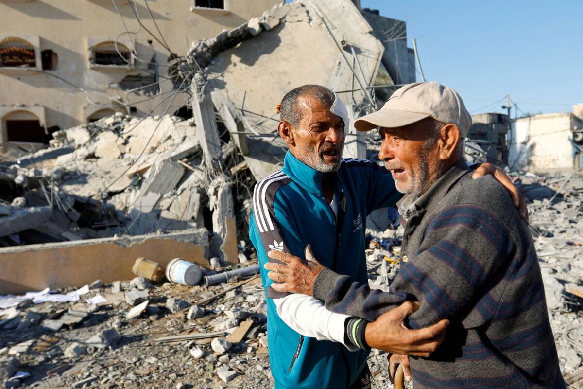 الرجل الفلسطيني محمد أبو دقة، الذي نجا من الغارات الإسرائيلية التي أسفرت عن مقتل 8 من أفراد عائلته وما زال يبحث عن ثلاثة آخرين ما زالوا محاصرين تحت أنقاض منزله، يتفاعل مع قريب له أمام الأنقاض في خان يونس جنوب قطاع غزة يوم الأحد. .  – رويترز