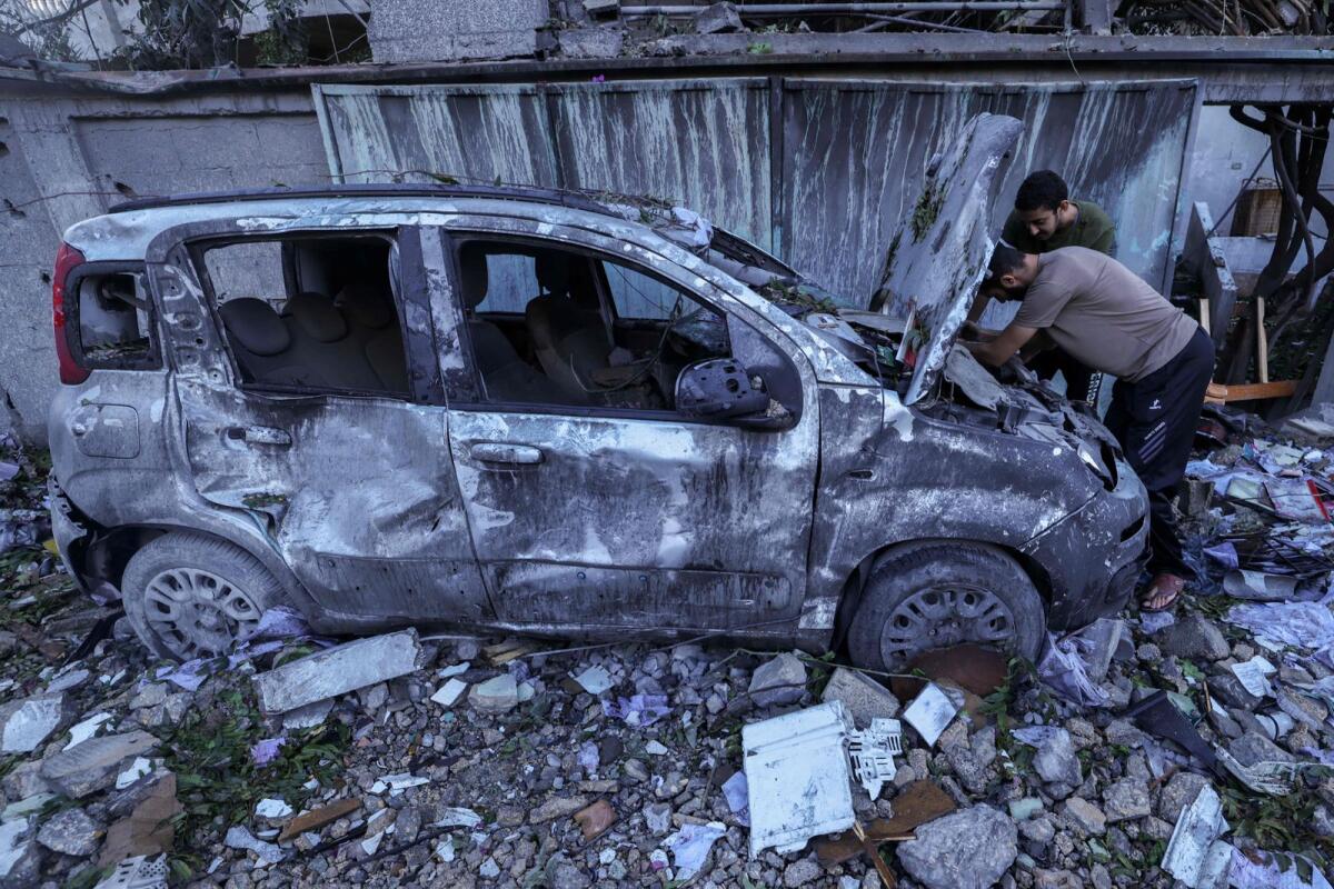 فلسطينيون يتفقدون سيارتهم المدمرة بعد غارة جوية إسرائيلية على مخيم رفح للاجئين جنوب قطاع غزة، يوم الاثنين.  – وكالة فرانس برس