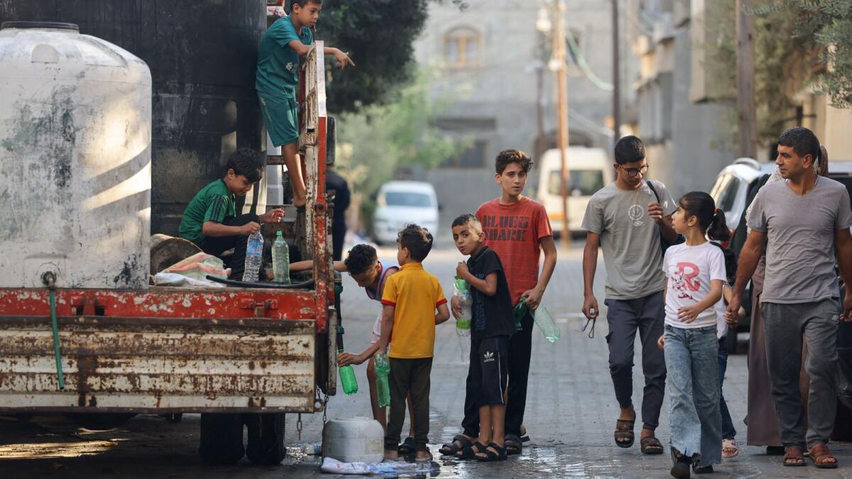 فتيان فلسطينيون يملأون زجاجات المياه من صهريج متنقل في رفح جنوب قطاع غزة.  – وكالة فرانس برس