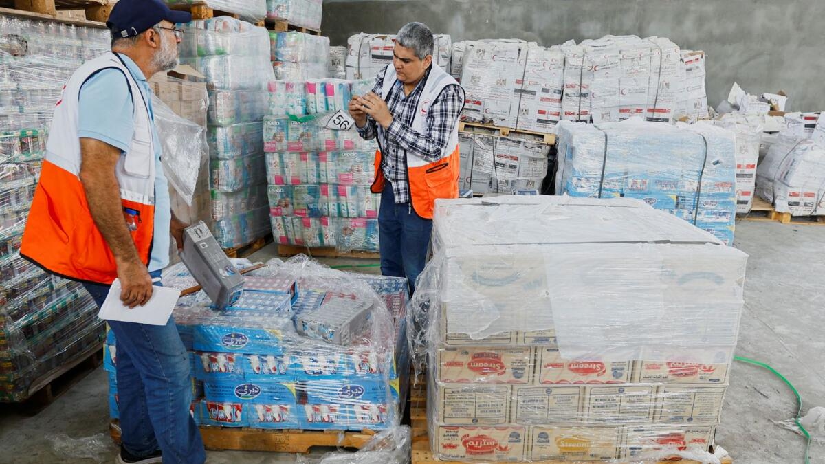 عمال الهلال الأحمر يقومون بفرز المساعدات قبل توزيعها على الفلسطينيين.  – رويترز