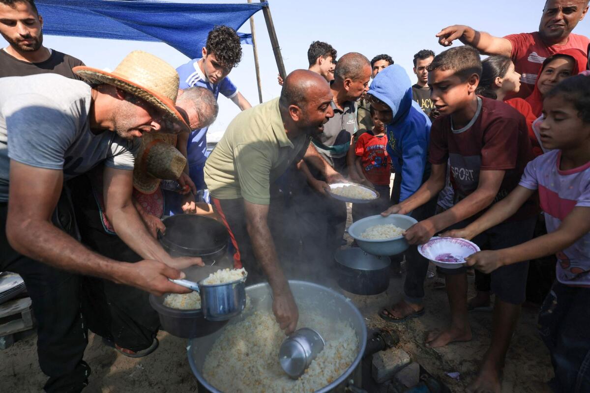 أشخاص يوزعون الطعام على الناس في مخيم مؤقت للنازحين في خان يونس بجنوب قطاع غزة في 25 أكتوبر 2023، مع استمرار المعارك بين إسرائيل وحركة حماس الفلسطينية.  الصورة: وكالة فرانس برس