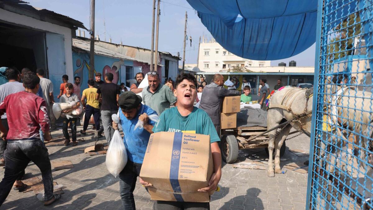 فلسطينيون يقتحمون مركز إمدادات المساعدات الذي تديره الأمم المتحدة والذي يوزع الغذاء على العائلات النازحة في أعقاب دعوة إسرائيل لأكثر من مليون من سكان شمال غزة للانتقال جنوبًا حفاظًا على سلامتهم، في دير البلح.  – وكالة فرانس برس