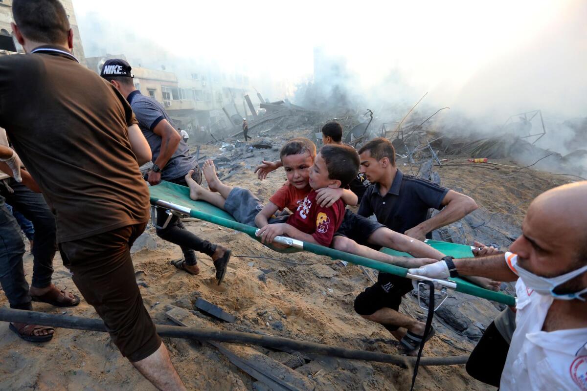 فلسطينيون يقومون بإجلاء صبيين مصابين من بين الدمار الذي أعقب الغارات الجوية الإسرائيلية على مدينة غزة، الأربعاء، 25 أكتوبر 2023. الصورة: AP