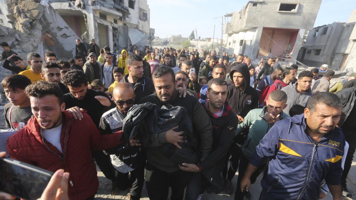 فلسطيني يحمل أحد أقاربه الذي قتل في القصف الإسرائيلي على قطاع غزة في رفح.  - ا ف ب