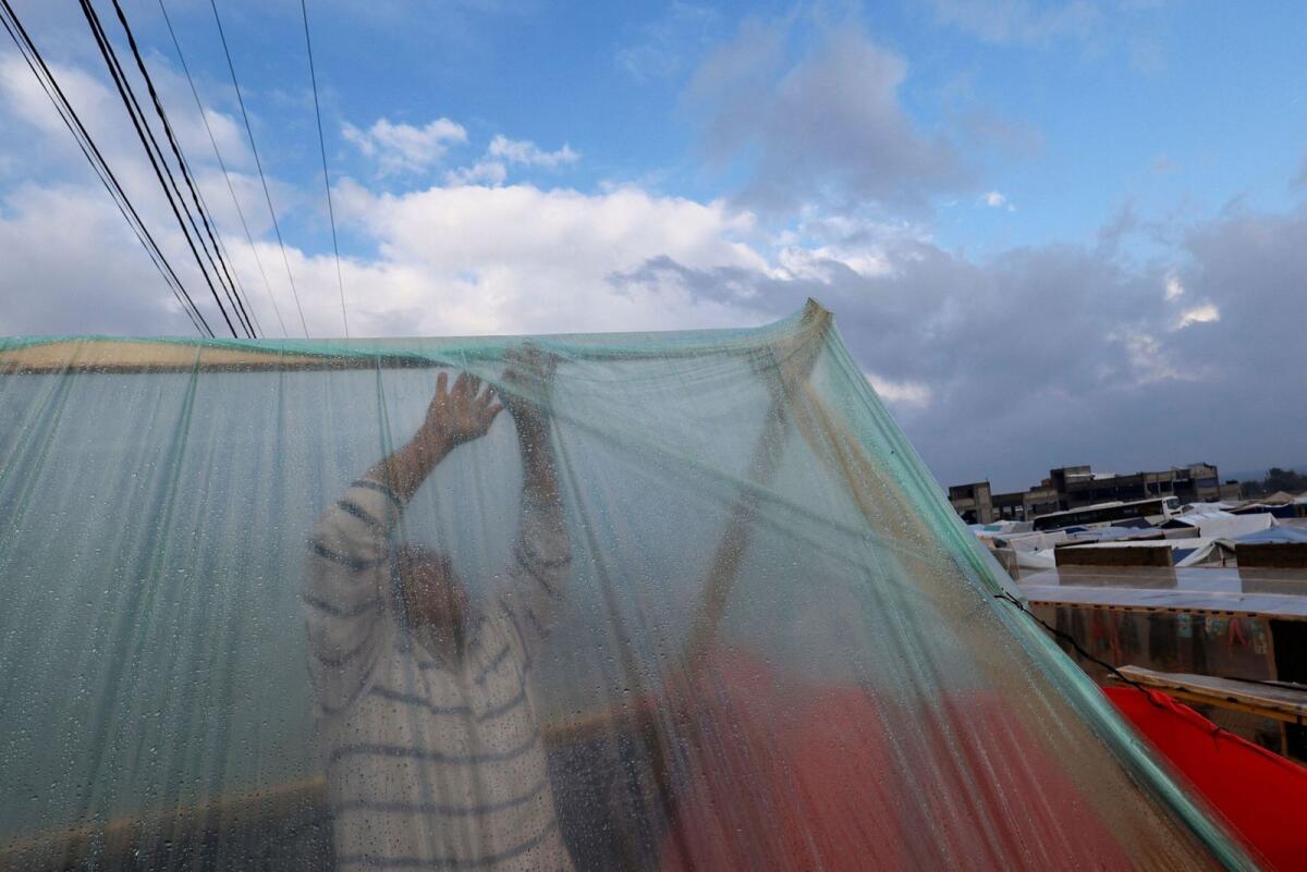 نازح فلسطيني يعدل خيمته بعد هطول أمطار غزيرة