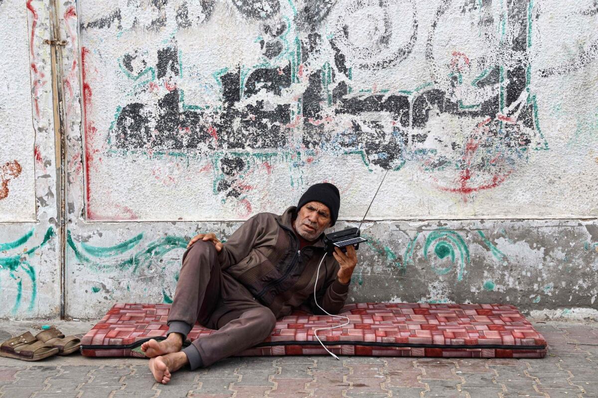 رجل عجوز فلسطيني يستمع إلى الراديو الخاص به في مخيم للاجئين في رفح بجنوب قطاع غزة في 17 ديسمبر. – وكالة فرانس برس