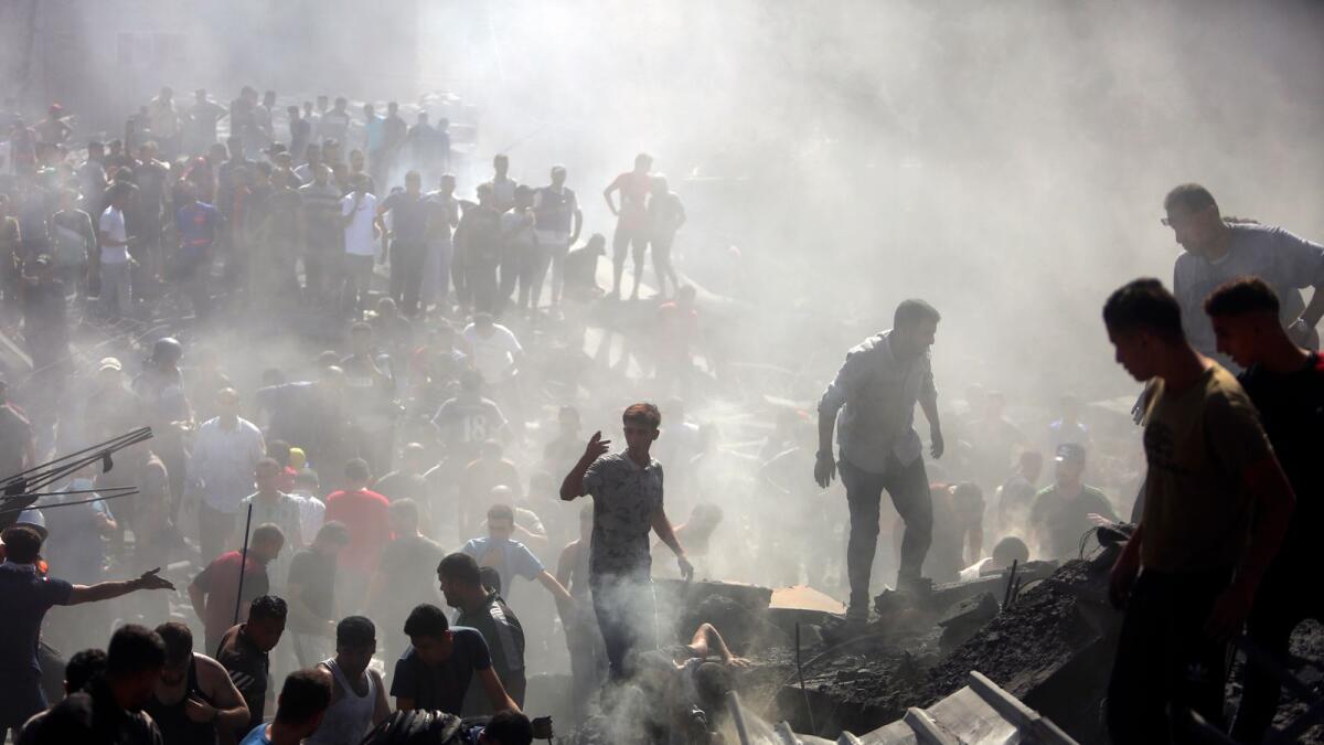 فلسطينيون يتفقدون أنقاض المباني المدمرة بعد الغارات الجوية الإسرائيلية على مدينة خان يونس.  — ا ف ب