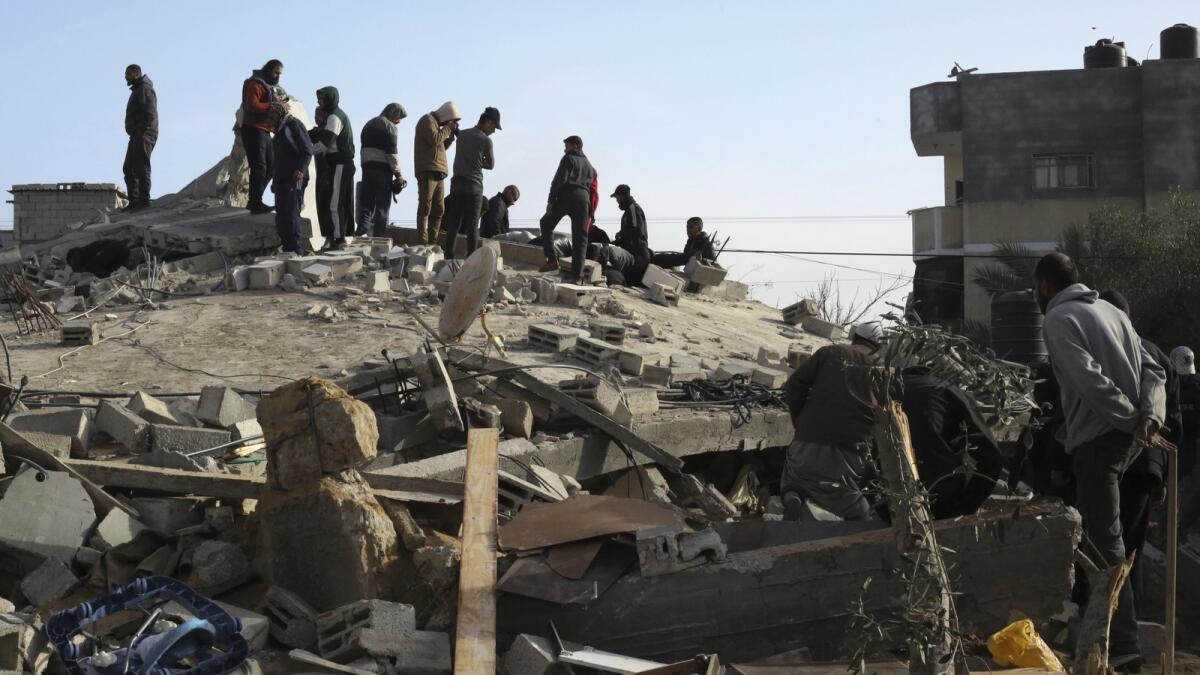 فلسطينيون ينظرون إلى الدمار الذي خلفته غارة إسرائيلية على مبنى سكني في رفح.  — ا ف ب