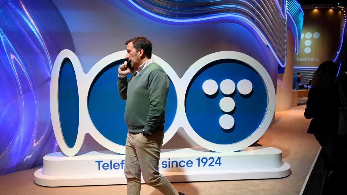 زائر يتحدث عبر الهاتف ويمر بجوار شعار Telefonica أثناء المؤتمر العالمي للهواتف المحمولة (MWC) في برشلونة.  – ملف وكالة فرانس برس