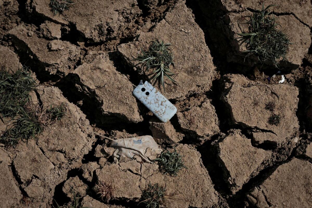 حافظة هاتف محمول مطروحة على الأرض بعد جفاف المياه من بحيرة نالوراهالي، الواقعة في بنغالورو، والتي تواجه نقصا في المياه.  – رويترز