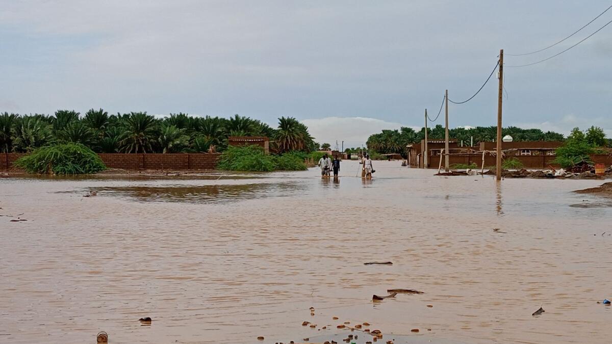 سودانيون يسيرون في شارع غمرته المياه في بلدة تنجاسي في ولاية مروي السودانية على بعد نحو 300 كيلومتر شمال العاصمة الخرطوم يوم الثلاثاء. أ ف ب