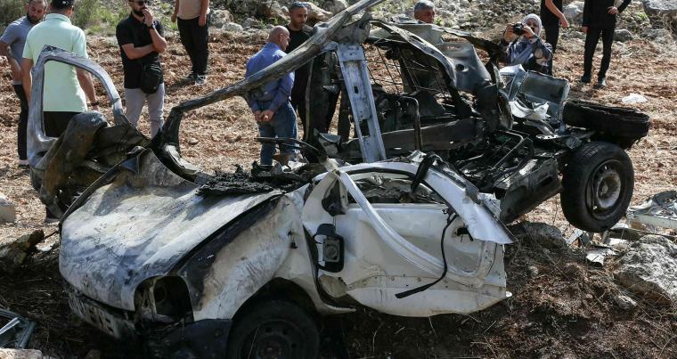 أشخاص يتفقدون حطام مركبة استهدفتها غارة إسرائيلية في قرية حاروف بجنوب لبنان، في 25 أكتوبر، 2025.